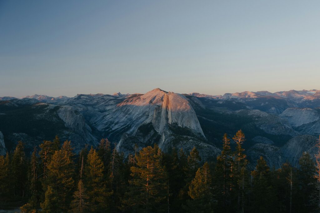 mountains at sunset with forest in front of it and a clear sky behind it